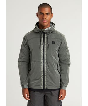 The Ortega is a regular fit summer jacket made from garment dyed polyamide for a unique color. It features a 2-way zip with tonal webbing tape, 2 side pockets, and an interior pocket with a zipper. Signature details include the CHASIN' comma badge and branded cord stoppers. The lining is made from polyester mesh.