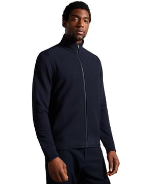 Mejora tu comodidad y estilo con la chaqueta Ted Baker Phloem con cremallera completa. Confeccionada con algodón de alto gramaje 100%, esta chaqueta ofrece una sensación premium y una comodidad inigualable. Cuenta con un acabado acanalado, un elegante cuello alto y un cierre de cremallera completo, que combina simplicidad con un toque moderno. Las mangas largas y el diseño refinado la convierten en una opción versátil, perfecta para superponer o llevar por sí sola. Ya sea que te vistas para una salida casual o para un look más elegante, esta chaqueta te mantendrá abrigado y con un estilo impecable.