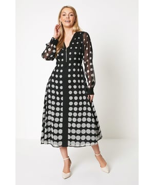 Zip front midi dress crafted from woven fabric
Flattering V-neckline with long sleeves
Allover polka dot print in a contrasting border pattern
Flared A-line skirt with a swishy midi length
Effortless pull-on style for easy dressing

This polka dot midi dress exudes sophistication with its striking border print and feminine silhouette. The zip front design offers a modern twist, while the flared skirt creates a flattering shape. Style with heeled sandals and a clutch for a chic daytime look perfect for casual events or family gatherings. The woven fabric ensures a comfortable yet glamorous feel.