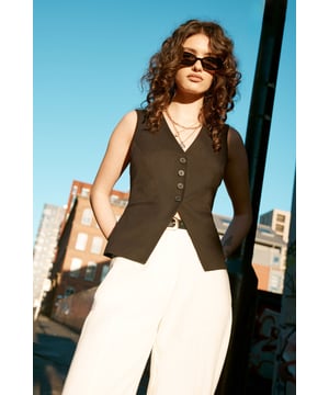Sleek tailored vest with a V-neckline
        Front button closure for a polished look
        Adjustable back belt for a customised fit
        Textured fabric adds visual interest
        Versatile piece for layering or wearing alone
    
    Embrace sophisticated style with this Essentials Tailored Vest from NastyGal. Perfect for the modern professional, this vest offers a refined silhouette that can effortlessly transition from day to night. Pair it with wide-leg trousers and a crisp white shirt for a chic office ensemble, or wear it solo with tailored shorts for a smart-casual look. The adjustable back belt allows for a personalised fit, ensuring you look impeccable whether you're presenting in the boardroom or networking at after-work drinks. For a fashion-forward twist, layer it over a long-sleeved bodysuit and team with straight-leg jeans and pointed flats. This versatile piece is a must-have for any wardrobe, offering endless styling possibilities while maintaining a professional edge.