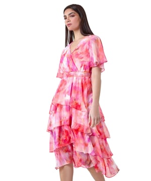Abstract Print Chiffon Tiered Midi Dress from Roman. Discover pure elegance with this abstract print tiered midi dress from the Ariella collection. This wedding guest staple features a soft chiffon fabric with a flattering tiered silhouette and a v-neckline. Designed with a wrap front and shirred stretch waist for a fit and flare shape, this will be flattering for any formal event. The vibrant abstract print, split detail skirt, and short floaty sleeves add a touch of femininity to the finished look. Whether you're ready for a day at the races or you're Mother of the Bride, this dress is easy to pull on overhead and style with heels for timeless occasionwear.