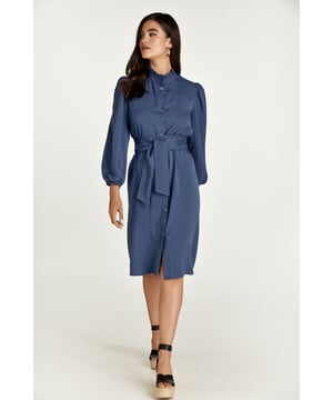 Este vestido índigo de manga larga está confeccionado en tencel tejido. Tiene fruncidos en los hombros y elástico en los puños creando fruncidos. Tiene escote redondo cerrado con cuello alto fruncido. Tiene una tapeta en la parte delantera y se abrocha con botones decorativos. El vestido puede llevarse con o sin cinturón. El cinturón está incluido.
