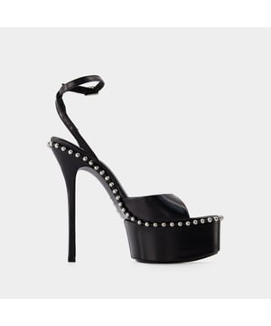 Las sandalias de tacón Nova 145 de Alexander Wang son la mezcla perfecta de elegancia y chic contemporáneo. Para complementar su llamativo diseño y su elegante silueta, combínalas con conjuntos atrevidos y sofisticados a la vez. Considera combinarlas con un maxivestido con aberturas para un look de noche glamuroso y moderno, o con un mono entallado con accesorios minimalistas para un conjunto potente y a la última. Estas opciones resaltan las elegantes líneas de las sandalias y la mezcla de lujo y estilo vanguardista característica de Alexander Wang, creando un look cohesionado y elegante. Ideal para eventos de alto nivel, cócteles o veladas de moda, esta combinación pone de relieve la capacidad de los tacones Nova 145 para realzar cualquier atuendo con un toque de dramatismo y sofisticación. Colores: Negro. Material principal: capretto. Material de la suela: cuero. Material del forro: capretto. Cierre: correa de tobillo con hebilla. Forma de la punta: punta puntiaguda. Ajuste: fiel a la talla - Tallaje: europeo.