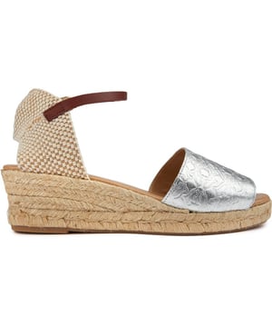 Eleva tu estilo de verano con las sandalias Radley Glasshouse Walk Alpargatas. Estas sandalias de cuero metalizado cuentan con un elegante tacón de cuña envuelto en cuerda de 6 cm y una plantilla acolchada para comodidad durante todo el día. El cierre de hebilla delgada garantiza un ajuste perfecto. mientras que la suela con borde de cuerda aporta un toque rústico de alpargata. Ideal para paseos por la ciudad o descansar junto al mar. este par es imprescindible para salidas de verano con estilo.