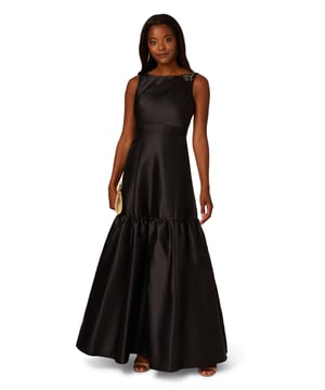 With details this luxurious, you will feel like royalty in this sleeveless ball gown. This formal dress features a sleeveless bodice, boat neckline, and a soft skirt with flounce hem. Designed with shining mikado fabric, this classic evening gown is pleated at the shoulder and accented with stunning stone trim. A hidden zipper closure at the centre back completes this black-tie dress. From charity balls to weddings, this sleeveless mikado gown will shine with a simple clutch and neutral heels.