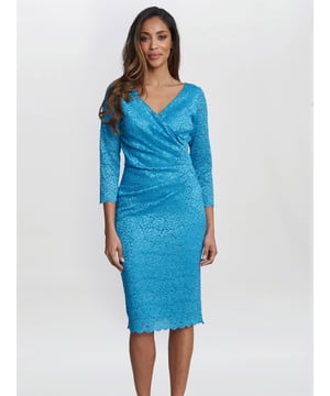 Look stunning in this beautiful dress by Gina Bacconi. Crafted in a stretch floral lace it features a wrap top bodice with a gathered side to create a flattering silhouette and a v shaped neckline front and back. This dress is lined with sheer sleeves with a scalloped hem and sleeve detail.