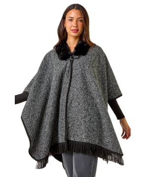 Faux Fur Fringe Hem Poncho from Roman. This style is ONE size.  Wrap up in style with this chic fringe detail poncho. Featuring a luxurious fur trim collar for added elegance and a trendy fringe hem for a playful finish, this poncho is the perfect layering piece for the Autumn/Winter season. Throw it on over your favourite knitwear and jeans for a fashion-forward look that will keep you both warm and stylish throughout the colder months!