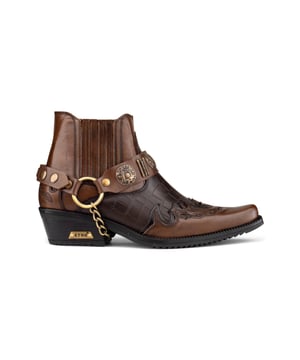 Las winklepicker son un estilo popular de botas, que se usan desde la década de 1950 y son las favoritas entre los artistas británicos de rock and roll a lo largo del tiempo. Este par está diseñado en un elegante marrón de dos tonos e incluye la característica distintiva de las winklepicker, que es la punta afilada, así como una silueta de botín tradicional y un tacón cubano vintage de 2". Esta pieza se caracteriza por la introducción de una elegante textura de piel de cocodrilo, así como diseños de paneles cosidos en la puntera y el talón y un diseño con volantes en los laterales. Esta bota se completa con la incorporación de una característica de correa de triple arnés, que está conectada por un anillo de metal y presenta insignias metálicas y tachuelas para crear una estética llamativa. • Elaboradas con cuero de vaca genuino con textura de piel de cocodrilo • Presenta una distintiva punta puntiaguda, un tacón cubano de 2" y una caña alta hasta el tobillo • Característica de correa metálica de triple arnés • Marca ETOR adornada en la suela