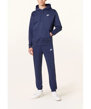 Der Nike Sportswear Club Fleece Hooded Trainingsanzug kombiniert klassischen Stil mit dem weichen Komfort von Fleece. Er verfügt über eine Kapuze und eine Trainingshose mit gebürstetem Fleece auf der Rückseite für winterliche Wärme. Gerippte Taille und Bündchen. Elastisches Taillenband mit Bindebändern. Gesticktes Markenlogo auf der Brust und den Jogginghosen. Produktnummern: 804346, 804406 0451.