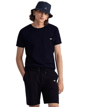 Gant introduces a mens t-shirt and shorts set with a small-scale embroidered shield graphic on the chest. Made of soft cotton and featuring a ribbed neckline, this tee showcases the iconic GANT logo. Crafted for everyday wear, the regular-fit tee is both comfortable and sustainable with Better Cotton. The included sweat shorts, also made of soft cotton blend, feature a ribbed waistband, three pockets, and a drawstring waist. The shorts are adorned with a small-scale embroidered shield graphic.