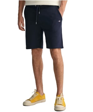 These classic sweat shorts are crafted from a soft cotton blend and tailored for a regular fit. Featuring a ribbed waistband for enhanced comfort, the design includes two front pockets, a single back pocket, and a drawstring waist. Completing the look, the shorts are adorned with a small-scale shield graphic embroidered on the left leg.