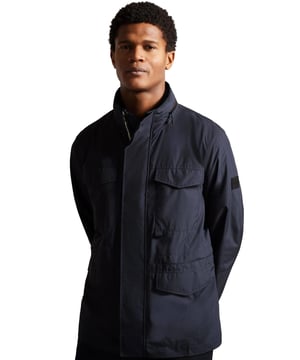 The Ted Baker Nylon Field Jacket in Navy offers a blend of style and versatility, perfect for any occasion. Designed with buttoned pockets for secure storage and featuring a branded badge on the sleeve, this jacket showcases Ted Baker's signature attention to detail. Practical elements like buttoned cuffs and a packaway hood tucked into the collar ensure you're ready for changing weather conditions. Made from premium materials, this field jacket combines functionality with a modern look, making it an essential addition to your wardrobe.