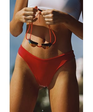 Code Danger Red. Our signature colour commands attention with this seamless bikini bottom — perfect for poolside hangs or deep dive endeavours. Take your look to the next level with the white cut-out one-shoulder bikini top for the full look.