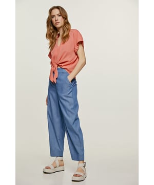 Diese indigoblaue Hose in voller Länge ist aus gewebter Baumwolle im Denim-Stil gefertigt. Die Hose wird mit einem verdeckten Reißverschluss und einem dekorativen Kunststoffknopf auf der Vorderseite geschlossen. Sie verfügt über einen breiten Bund mit Gürtelschlaufen und seitliche Innentaschen. Unterhalb des Bunds befinden sich zwei Abnäher. Der 5 cm breite Saum mit Abnähern darüber sorgt für einen dezenten Blousoneffekt. Diese Hose ist in einer lockeren Silhouette gestylt.