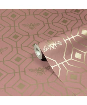 Make your boudoir buzz with the Bee Deco wallpaper featuring a honeycomb inspired geometric design completed with buzzing bumble bees. A soft blush hue sits behind metallic gold foil, bringing a contemporary colour scheme into your home. This wallpaper is a paste the wall application; simply paste the wall, hang your paper, and leave to dry. Each roll is 10m long and 52cm wide. Pattern repeat: 53cm Straight match. Our Bee Deco wallpaper can be used to paper the whole room or to create an eye-catching feature wall. This wallpaper is also wipeable so that any light marks can be dabbed away.