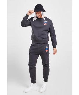 Nike Standard Issue fleece trainingspak in donkerrookgrijs. Hier worden tassen en tassen met stijl tentoongesteld, maar dit mag niet ten koste gaan van het comfort. Gemaakt van zachte, katoenrijke fleecestof in een zeer functionele en sportieve esthetiek. Het materiaal is aan de achterkant licht geborsteld voor superieure zachtheid. Met een elastische, verstelbare tailleband met trekkoord, op joggers geïnspireerde geribbelde manchetten, steekzakken en cargozakken op de pijpen.