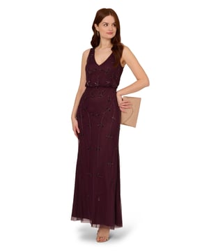 Put a little sparkle on display when you rock this sleeveless blouson gown. This formal dress features a sleeveless blouson bodice, deep v-neckline and back, and a soft skirt. Crafted with a luxe mesh fabric that is fully lined, this evening gown is embellished with sequin and beaded vines. The neckline and armholes of this gown are trimmed in beading for added sparkle. A hidden zipper closure at the centre back completes the design. This sleeveless beaded gown is a stunning look for a wedding guest or bridal party and pairs well with neutral or metallic accessories.