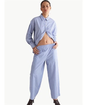 Kaufen Sie eine detaillierte, elastische und geschnürte, weite Hose aus gestreifter Baumwolle. Die dünnen Streifen auf der Hose sorgen für eine lange und schlanke Silhouette und verleihen dem Stil eine elegante Note. Diese gestreiften Details verleihen der Hose Bewegung und Lebendigkeit und heben sie von der Einfachheit ab. Sie bietet verschiedene Kombinationsmöglichkeiten, um jeden Stil zu passen. Sie kann leicht mit Blusen, Hemden oder Pullovern kombiniert werden und eignet sich für verschiedene Anlässe von Freizeitkleidung bis zu besonderen Veranstalt