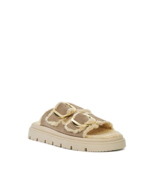The ultimate in comfort and style our Lodge two bar mules feature two large gold buckles, a cosy faux shearling footbed with a gold embossed logo, and they rest on a chunky lightweight grip sole.  Wear them to the gym, shopping, for brunch with friends...Lodge really is the perfect off duty shoe. Crafted from premium materials, Lodge is available in a sand taupe and textured black leather.