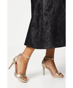 Elegant faux leather heeled sandals with a platform sole
Ankle strap with metallic buckle fastening for a secure fit
Open toe design to elongate the leg
Towering stiletto heel height of 7-9cm
Metallic finish exudes sophistication and glamour

Crafted with meticulous attention to detail, these Talia Platform Heeled Sandals from Coast are the epitome of refined elegance. Designed to make a statement at formal occasions like weddings, races, or graduations, these sandals radiate luxury. Style them with a floor-length gown or a tailored midi dress for a polished and sophisticated look that commands attention. Embrace the allure of these sandals and let them be the centerpiece of your ensemble, elevating your confidence and poise for an unforgettable evening.