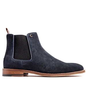 Botas Chelsea para hombre en azul Simon Carter Elgar 2, con parte superior de suave ante, finos detalles, lengüeta de tela de marca de diseñador en el talón y forro y calcetines impresos exclusivos. Estos elegantes y exclusivos zapatos para hombre de Simon Carter son tu básico con estilo para muchas ocasiones.
