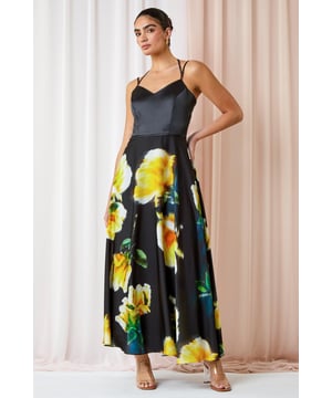 Luxe Floral Fit & Flare Maxi Dress from Roman. Feel glamorous in this luxurious floral maxi dress. Designed in a glamorous silhouette that cinches you in at the waist, this fit and flare gown features a strappy bodice with gold toggles. A flattering v-neckline and tie at the back adds more femininity to the dress, finishing at a floor sweeping full length. It has a romantic floral print, adjustable cami straps and concealed back zip to fasten. From Summer Weddings to formal dinners, this special occasion dress is sure to turn heads at any event this year.