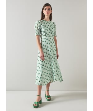The Tabitha dress is crafted from a silk-blend spot jacquard in morning mist green with a 1930's hand painted primula print reimagined from vintage archives. It has a round neck, puff shoulders, short shirred sleeves, pleating at the bust, a floaty shape and a dipped midi-length hem.