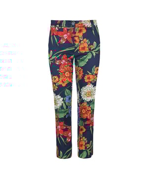 Este pantalón de corte 7/8 está confeccionado en gabardina elástica con motivos florales en tonos rojo, azul y verde. Cintura de 5 cm con trabillas del mismo tejido. Se abrocha por delante con un botón blanco de tejido natural y una cremallera blanca oculta. Bolsillos con aberturas diagonales a los lados. En la parte exterior del bajo hay una abertura redondeada. Estos pantalones son ecológicos.