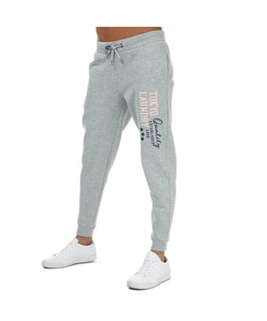 Tokyo Laundry Biscuit-joggingbroek voor dames in gemêleerd lichtgrijs.<br /><br />- Elastische tailleband met trekkoord.<br />- Zakken met zijnaden.<br />- Taps toelopende pijpen met geribde boorden.<br />- Tokyo Laundry-motief gedrukt op de linkerdij.<br />- Zachte katoenrijke geborstelde fleecestof.<br />- Normale pasvorm.<br />- De binnenbeenlengte is ongeveer 74 cm (29 inch).<br />- 55% katoen, 40% polyester, 5% viscose. Machinewasbaar.<br />- Ref: 3F17037<br /><br />Afmetingen zijn bedoeld als richtlijn.