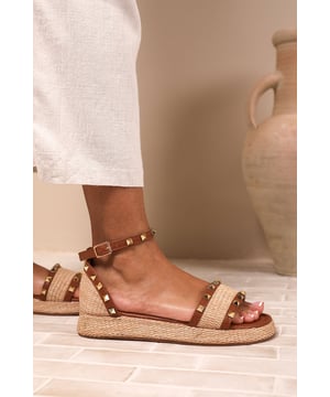 Elevate your summer wardrobe with these Katara Studded Gladiator Braided Strap Espadrille Flatform. Perfect for casual outings or stylish beach strolls, these sandals blend comfort and elegance effortlessly. Designed with comfort and elegance in mind, these sandals feature a woven rattan sole, perfect for casual outings or semi-formal occasions
Key Features:-


Design: An adjustable ankle strap and toe band with sleek metallic stud embellishments create a trendy, modern look that’s both stylish and functional.

Durable Construction: The premium woven raffia base, durable faux leather straps, and slip-resistant outsole ensure long-lasting wear, stability, and support.
Comfortable Fit: A softly cushioned insole offers all-day comfort, while the low wedge heel provides subtle height for extended wear without compromising on practicality.
Specifications:
Material: Faux leather upper, synthetic insole, rattan-textured sole
Sole Type: Flat espadrille design with durable rubber outsole
Closure: Adjustable buckle ankle strap
Invest in our Katara Studded Gladiator Braided Strap Espadrille Flatform and enjoy the perfect combination of style and comfort. These flats will elevate your outfits and leave you feeling effortlessly fashionable throughout the day. Whether paired with sundresses, denim shorts, or flowy skirts, these sandals add a touch of sophistication to any outfit. Step into summer style today!