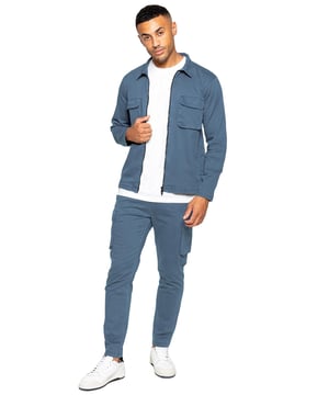 Enzo Heren Cargo Outfit Set. Lang mouw, ritssluiting, met kraag, cargo overshirt. Twee platte cargozakken aan de voorkant met klittenbandsluiting. Twee zijzakken met bies. Gestikte boorden aan de mouwen en zoom. Set compleet met cargobroek. Regular fit, rechte pijp, enzymgewassen. 5-pocket ontwerp: 2 zijzakken, 2 cargozakken met klittenbandsluiting en een enkele achterzak met bies. Elastische tailleband met verstelbaar trekkoord.