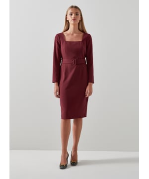 The Carrington shift dress is crafted from a recycled polyester blend in rich cabernet red. It's a square neck, fitted style with bracelet-length sleeves, a waist-cinching belt, and it falls to just below the knee.