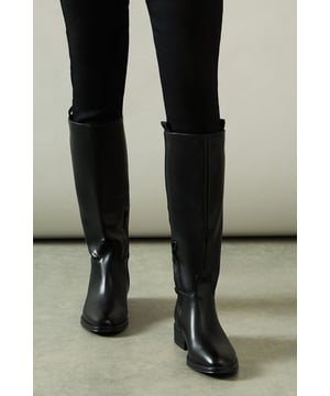 Knee-high riding boot design with sleek silhouette
        Faux leather construction for a polished look
        Distinctive stirrup detail adds equestrian flair
        Low heel measuring between 5 and 6.5cm for comfortable wear
        Side zip closure for easy on and off
    
    Step into sophistication with the Keely Faux Leather Stirrup Detail Low Heel Riding Knee Boot from Wallis. These elegant boots manifest a perfect blend of style and practicality, ideal for the woman who values both comfort and glamour. The knee-high silhouette elongates the leg, while the low heel ensures all-day wearability. Style these versatile boots with skinny jeans and an oversized jumper for a chic daytime look, or pair them with a flowing midi dress for family gatherings. The stirrup detail adds a touch of equestrian charm, making these boots a standout choice for casual outings or countryside walks. Whether you're running errands or meeting friends for brunch, these boots will keep you looking effortlessly stylish and feeling comfortable throughout your day.