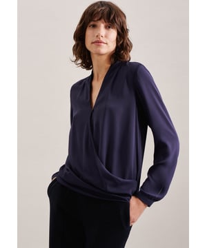 Drapierte Damen-Shirtbluse aus zartem Krepp-Gewebe aus der Schwarze Rose-Kollektion. Die feminine Bluse punktet mit einem modernen Look, der die weibliche Silhouette gekonnt betont. Ergänzende Details sind die schmalen Manschetten, das verlängerte Rückenteil und das fixierende, sichtbare Bündchen vorne. Rückenlänge beträgt 66 cm.