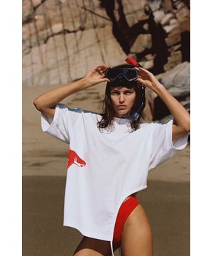 Dieses hochgeschlossene Cut-Out-T-Shirt ist tadellos aus hochwertiger Bio-Baumwolle gefertigt und zeigt den typischen LET'S SWIM-Hai-Grafikdruck, der an der Seite des Stücks hervorschaut. Das einzigartige Cut-Out-Design hat einen zusätzlichen Kordelzug, der beim Ziehen einen asymmetrischen Rüscheneffekt erzeugt – das perfekte Kleidungsstück zum Überziehen und Losgehen, egal ob nass oder trocken.