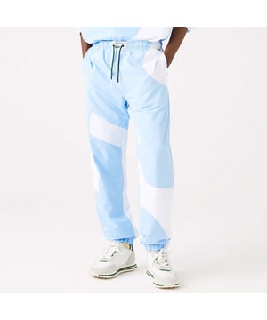 Men's Lacoste Heritage Graphic Track Trousers.- Water-repellent recycled polyester lightweight fabric.- Side pockets in front and back zip pockets.- Elasticised waistband with vintage label and drawstring.- Elasticised ankles.- Embroidered green crocodile on thigh.