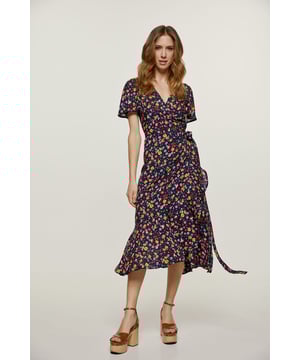 Dieses sommerliche Wickelkleid ist aus einem gewebten Stoff mit Blumendruck gefertigt. Es hat einen V-Ausschnitt und kurze Rüschenärmel. In der Taille wird es mit Bändern aus demselben Stoff geschlossen. Am Saum befindet sich eine 26 cm lange Rüsche. Das Kleidungsstück ist in Midi-Länge gestylt.