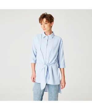 Een androgyne en elegante stijl. Dit shirt is verfraaid met panelen om op het midden te binden. Een tijdloos silhouet, gemonteerd of los. Draag het met jeans of legging voor de informele uitjes van de zomer.
Productdetails
• Vorm: recht
• Lengte: 73 cm
• Mouwen: 3/4 om op te rollen
•	Kraag
• Midden voorgeknoopt