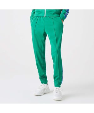 Men's Lacoste Héritage Contrast Bands Trackpants. Tapered fit, natural ease, carrot leg: Perfect for practice. Elasticised waistband: An ergonomic design. Side zip pocket: Made for your keys. Sewn silicone crocodile: Signature Lacoste performance. Material: 100% Polyester. Ref: XH0095HD2.