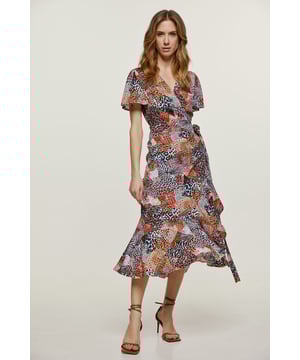 Este vestido cruzado de verano está confeccionado en tejido con estampado animal. Tiene escote en pico y manga corta con volante. Lazos del mismo tejido se abrochan en la cintura. En el dobladillo hay un volante de 26 cm. La prenda tiene un estilo de largo midi.