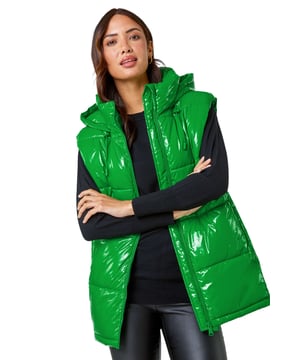 Patent Hooded Gilet from Roman. Add a pop of colour and a unique twist to your casualwear with our bold hi-shine gilet! The perfect layer for transitioning into Autumn, this cosy staple has a padded silhouette and cosy funnel neckline for warmth. With a secure zip fastening, this jacket also has drawstring detail and a glossy high shine finish. This statement jacket is a fashionable yet functional layering piece with zipped side pockets and a showerproof hood. Wear over relaxed denim and lightweight jumper for your own runway inspired outfit!
