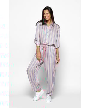 Deze stijlvolle broek met rechte pijpen, afkomstig uit de nieuwste Caroline Tensen Collectie, is bedrukt met verticale strepen in heerlijke zomerse pasteltinten. De gestreepte broek heeft een roze trekkoord in de taille. Je kunt zelf kiezen of je de broek strakker of losser wilt dragen, precies zoals jij het prettig vindt! De wijde broek heeft twee steekzakken aan de voorkant en soepel vallende pijpen. De Seattle broek combineert een gestreept patroon met een soepelvallende kwaliteit van modal, wat het ontwerp een relaxte uitstraling geeft. Maar dankzij de frisse pasteltinten is deze broek ook perfect geschikt voor een chique look. Voor een moeiteloze en stijlvolle outfit de hele dag door, kun je deze broek combineren met de bijpassende Memphis blouse voor een gecoördineerde look. Deze opvallende broek combineert gemakkelijk comfort met een vleugje glamour, waardoor het een onmisbaar item is voor elke modieuze garderobe. Combineer hem bijvoorbeeld met een stijlvolle nude pump en je bent klaar om te gaan! Liever een casual look? De broek is ook perfect voor een ontspannen dagje thuis op de bank. Gemaakt van 100% modal, biedt de Seattle broek het ultieme comfort en een luxe uitstraling. Modal voelt namelijk heel zacht, glad en soepel aan, met een subtiele glans.