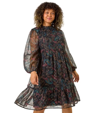 Curve Metallic Print High Neck Swing Dress from Roman. Get ready to dazzle in our metallic print Curve swing dress this Autumn Winter. The high neckline with delicate ruffle details and long cuff sleeves give an elegant touch, while the classic swing shape offers comfort and style. Crafted from a comfortable woven fabric in a striking paisley print with a metallic finish, this dress is perfect for both day and night. Style with your favourite winter boots and a cosy coat for an Autumnal look!