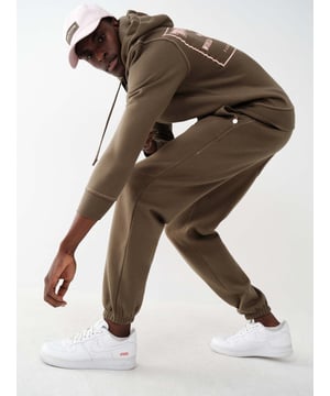 The Big T Logo Jogger is a true essential. Designed from a cozy cotton blend, this men's jogger sweatpant features an elasticized drawstring waistband and elasticized tapered hem. Finished with rivet detailed side pockets, back patch pocket, and contrast Big T stitching throughout.   