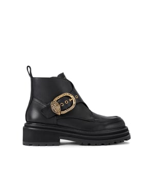 This Kurt Geiger Mayfair Chunky Ankle Boot features a black leather upper. There is a statement strap across the foot that is fastened with antiqued brass buckle finished with eagle head. Heel height: 5cm.