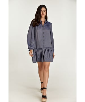 Este vestido de manga larga está confeccionado en tejido de viscosa estilo denim azul. Tiene cuello y tapeta en la parte delantera que se abrocha con botones decorativos de dos tonos. Las mangas tienen puños que se cierran con un botón. Hay fruncidos en los hombros y 12 cm por debajo hay una costura con fruncidos debajo. A 30cm del dobladillo hay una costura con frunces.