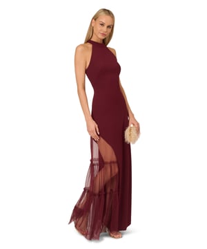 Raise a glass to celebrate all of your upcoming occasions in this eye-catching halter gown. This formal dress features a halter bodice, short mock neckline, and a fitted silhouette that is contrasted by a sheer mesh skirt with ruffle details. Designed with knit crepe that has some stretch and no waist seam for a comfortable and figure-flattering fit, this evening gown is perfect for a formal or black-tie dress code. A hidden zipper closure at the centre back completes this stunning dress. Styled with nude heels and a beaded clutch, this sexy yet sweet gown is a head-turner.