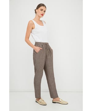 Pantalón largo en tejido, 100% lino. Cintura elástica con dos largos del mismo tejido con topes metálicos en el extremo que se pueden anudar. Dos bolsillos redondos a los lados. Más ancho en la parte superior y estrechándose hacia abajo. Nuestro modelo mide 178 cm y usa la talla 36. Medidas de la talla 38 (en cm): Largo del cuerpo: 101; cintura-37; Dobladillo-56. La prenda es holgada.