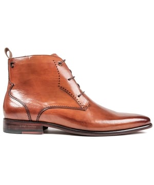Botas chukka color tostado Simon Carter Collie con cordones y parte superior de cuero liso. Refuerzo del talón textil de la marca del diseñador. lengua de marca. y logo de metal en el talón. Estas botas de punta tienen un estampado exclusivo de Simon Carter Queuing Dog. Forro de piel y suela y tacón de capas sintéticas.