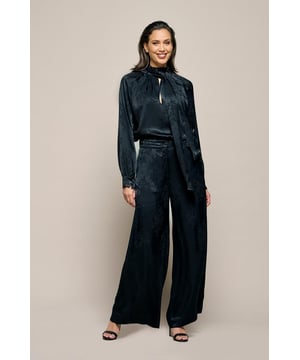 Ontdek de zwarte jacquard geweven broek, een perfect voorbeeld van stijl en comfort. Deze broek heeft een wijdvallende, rechte pasvorm die zowel elegantie als veelzijdigheid biedt, ideaal voor formele en casual gelegenheden. De hoge taille met elastiek aan de achterkant garandeert een perfecte pasvorm en optimaal draagcomfort. Voorzien van schuine steekzakken aan de voorkant en elegante strookzakken aan de achterkant, voegt deze broek een stijlvolle touch toe aan je outfit. Het jacquard geweven bloempatroon geeft de broek een subtiele textuur en een luxe uitstraling, waardoor het een tijdloze en verfijnde keuze is voor je garderobe. Combineer de broek met de bijpassende Bension blouse voor een elegante jumpsuit-look, of draag hem met een klassieke zwarte top voor een verzorgde dagelijkse outfit. Dankzij de hoogwaardige afwerking en het moderne design is deze zwarte jacquard broek een waardevolle aanvulling op elke modebewuste garderobe. Of je nu kiest voor trendy skinny jeans of klassieke broeken, Mart Visser biedt zorgvuldig ontworpen en kwalitatieve stukken die garant staan voor een stijlvolle uitstraling.